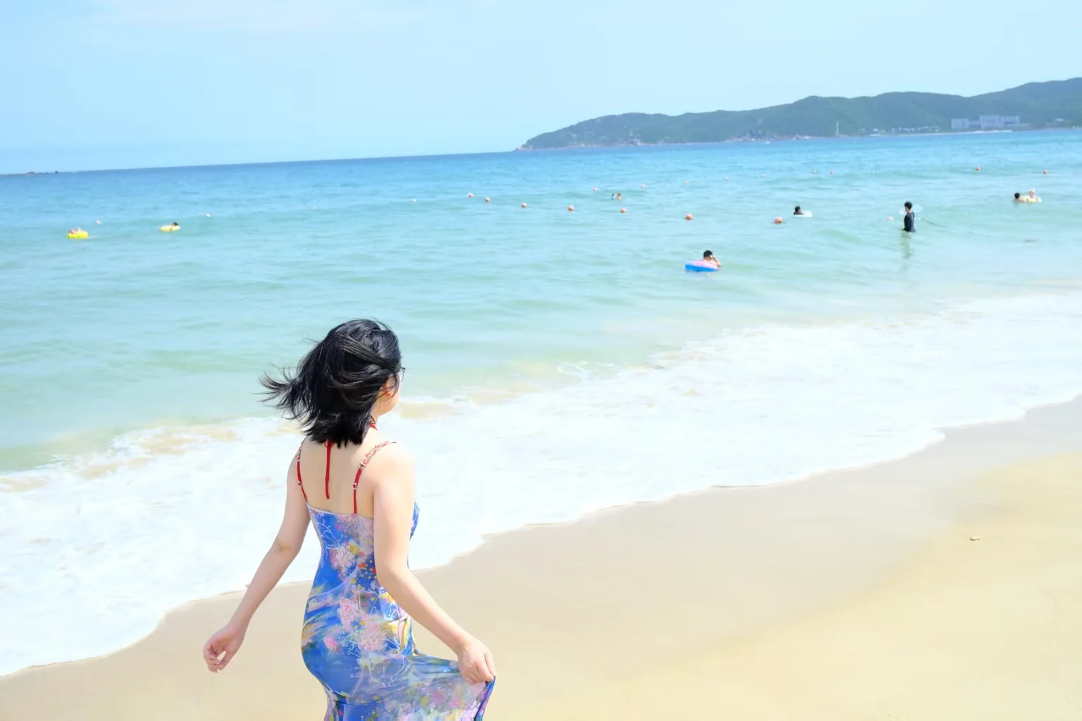 女子沿着明亮海岸走向海水